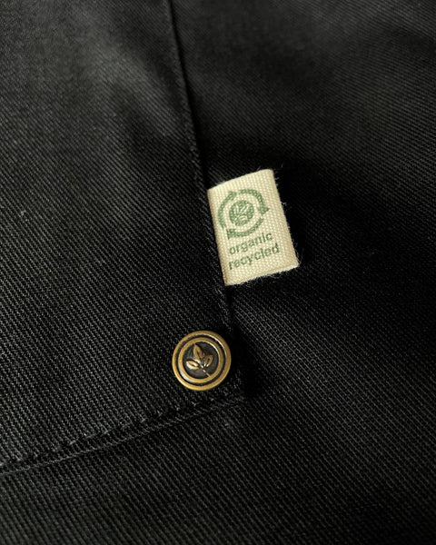 the corn of a pocket on a black apron that has a tan tag that says 