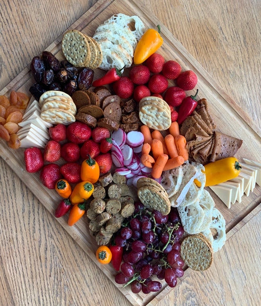 vegan charcuterie board with plant based meat, dairy free cheese, veggies, crackers, and fruit