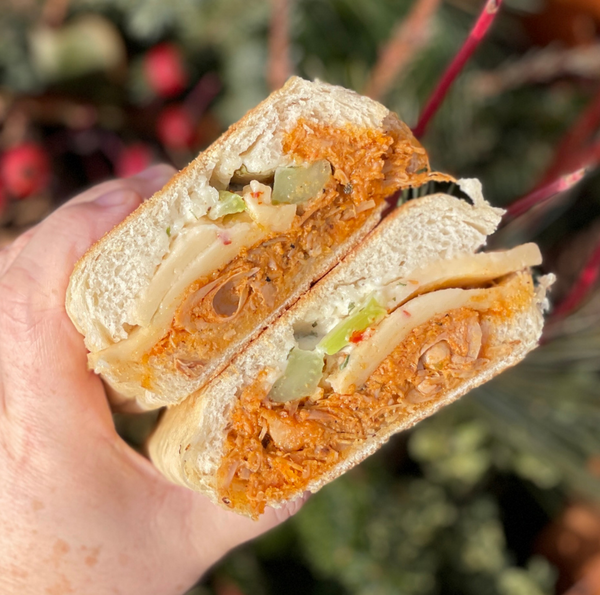 stacked halves of a vegan sandwich with jackfruit chicken, dairy free cheese, and celery