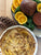 a vegan holiday ham roast surrounded by orange slices next to a bowl of dairy free truffle cheese potatoes