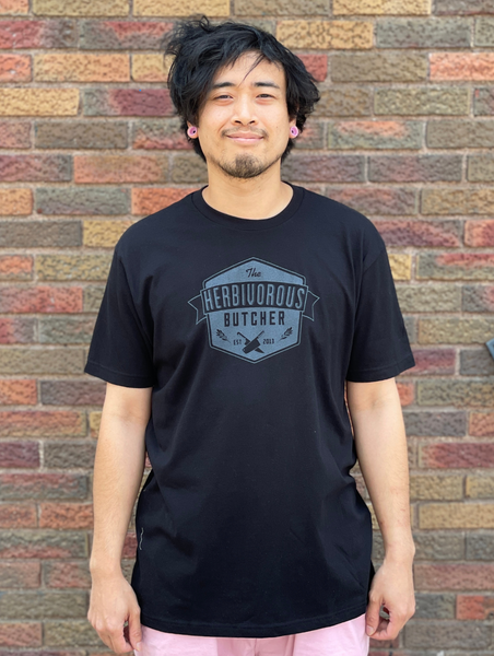 person wearing a black t shirt with The Herbivorous Butcher logo on it