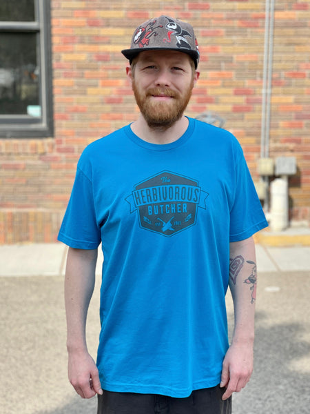 person wearing a blue t shirt with The Herbivorous Butcher logo on it