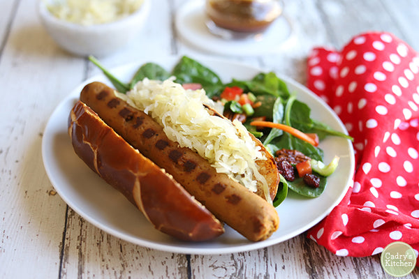 A vegan beer brat in a bun with a side salad on a plate