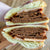 stacked halves of a vegan sandwich with lots of layers of plant based roast beef and dairy free cheese