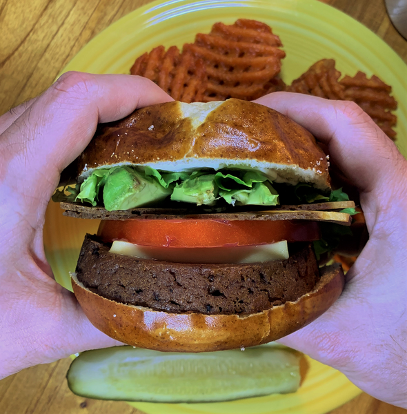 vegan burger with a pretzel bun, lettuce and greens