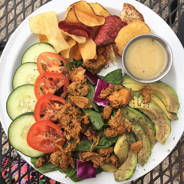 salad with vegan shredded chicken, avocado, greens, cucumbers, tomatoes and a side of chips